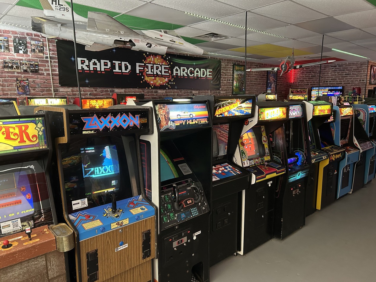 View of multiple arcade cabinets and a banner that reads 'Rapid Fire Arcade'.